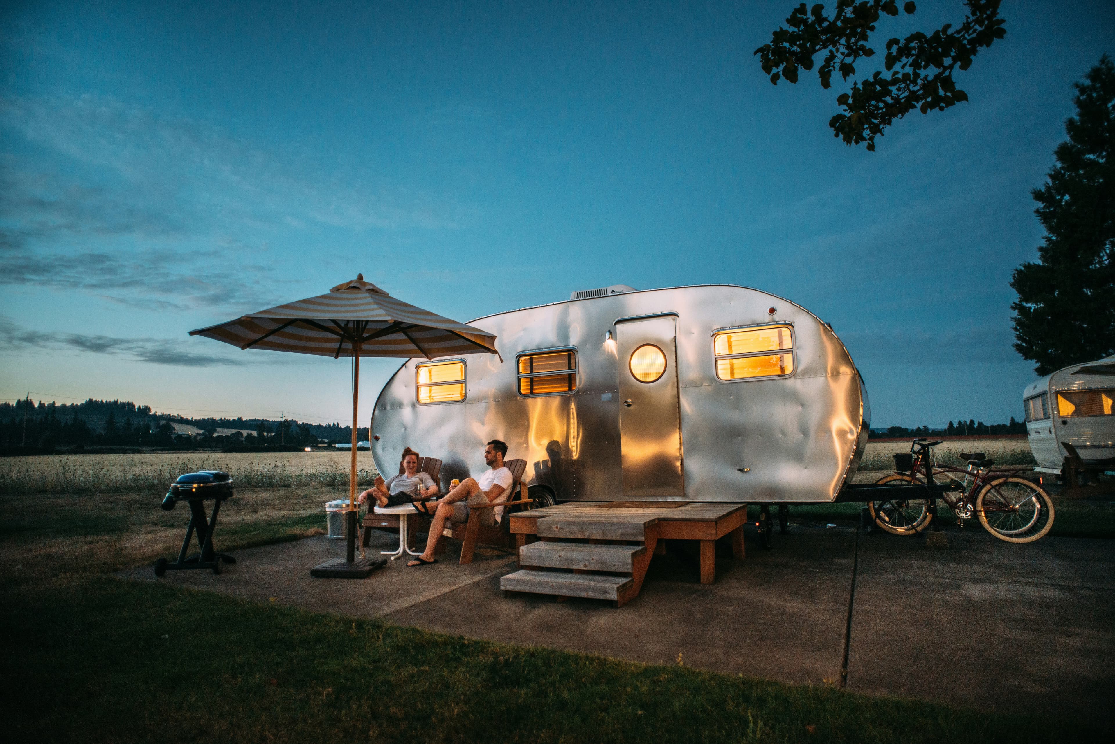 Couple sitting beside a motorhome watching the sunset over rolling hills